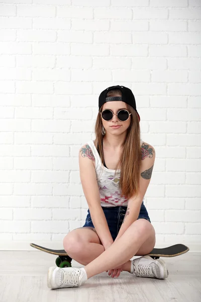 Πανέμορφο hipster κορίτσι με skateboard επάνω ελαφρύς υπόβαθρο — Φωτογραφία Αρχείου