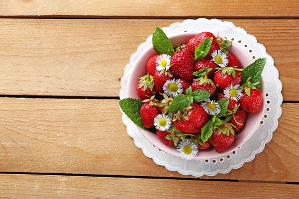 Red ripe strawberries in bowl, on color wooden background — Stock Photo, Image