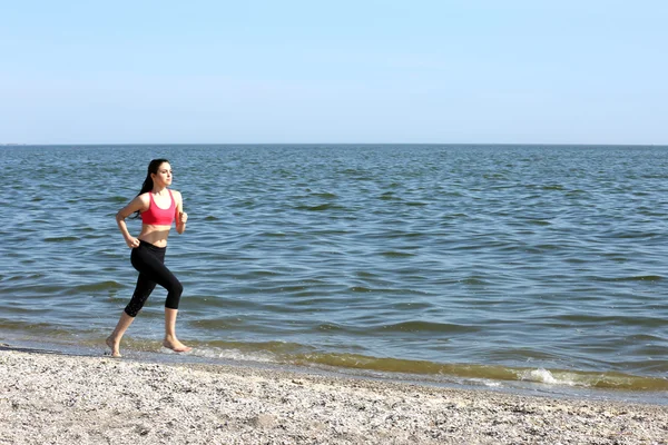 Mujer joven corriendo en la playa — Foto de Stock