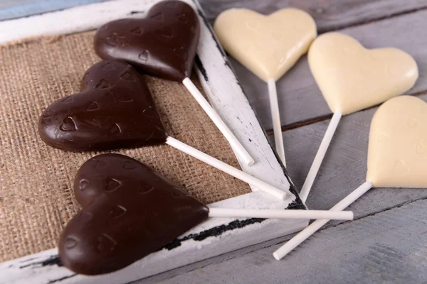 Chocolade hartvormige snoepjes op stokken op houten tafel, close-up — Stockfoto