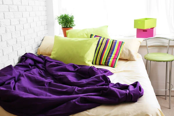 Cómoda cama con almohadas de colores y manta púrpura en el dormitorio —  Fotos de Stock