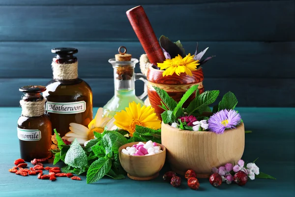 Kruiden, bessen, bloemen en pillen op een houten tafel achtergrond kleur — Stockfoto