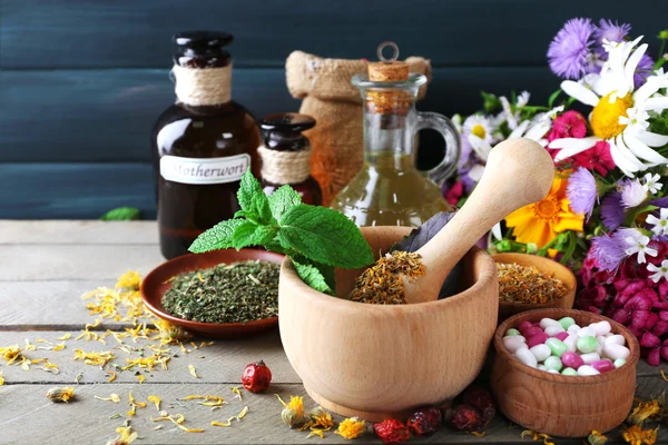 Kruiden, bessen, bloemen en pillen op een houten tafel achtergrond kleur — Stockfoto