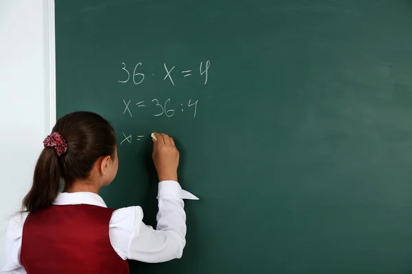 Mooi meisje schrijft op blackboard in klas — Stockfoto