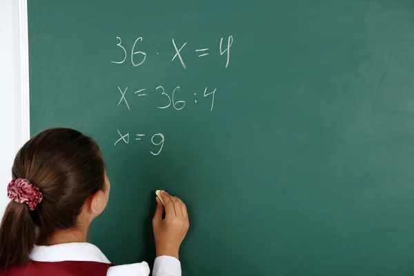 Mooi meisje schrijft op blackboard in klas — Stockfoto