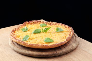 Fesleğenli siyah arka plan üzerine lezzetli peynirli pizza