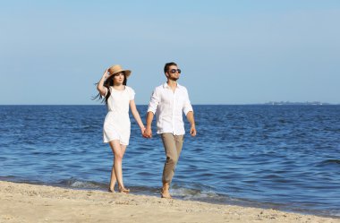 Genç bir çift sahilde yürüyor.