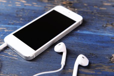 ahşap arka planda cep telefonu ve kulaklık