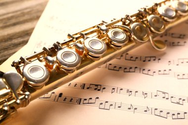 Ahşap masa üzerine müzik notlar ile gümüş flüt yakın çekim
