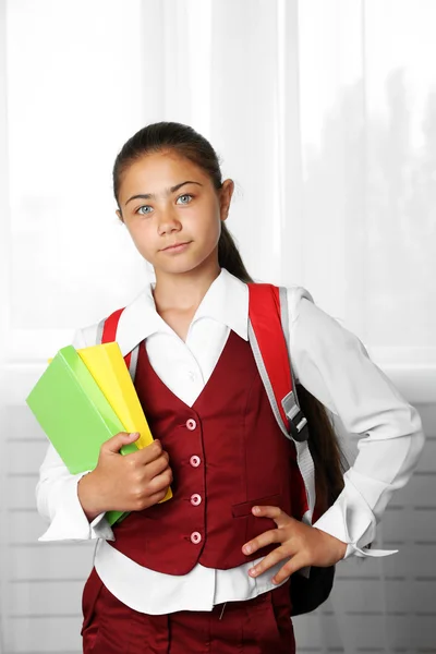 Schönes kleines Mädchen in Schuluniform mit Rucksack und Büchern — Stockfoto