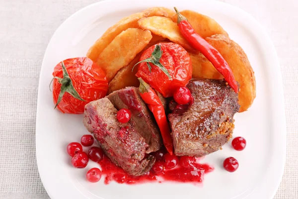 Sabrosa carne asada con salsa de arándanos y verduras asadas en el plato, sobre fondo claro — Foto de Stock