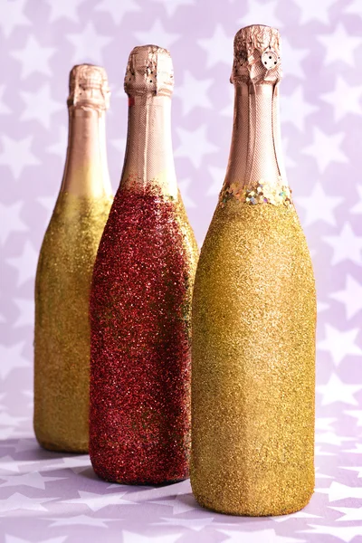 Ljusa flaskor champagne på papper bakgrund — Stockfoto
