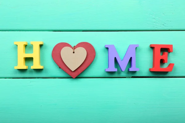 Letras decorativas formando palabra HOME con corazón sobre fondo de madera —  Fotos de Stock