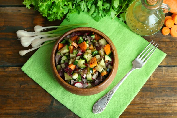 Trä skål med färska grönsaker sallad på Servett, ovanifrån — Stockfoto