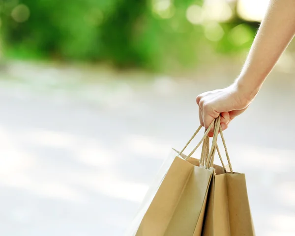 Mão feminina segurando sacos de compras ao ar livre — Fotografia de Stock