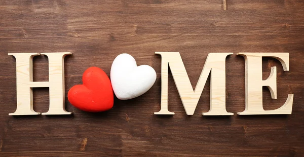 Декоративные буквы, образующие слово ДОМ с сердцами на деревянном фоне — стоковое фото
