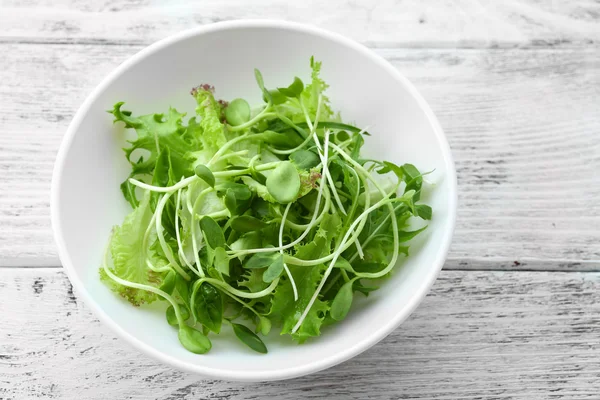 Frischer gemischter grüner Salat in Schüssel auf Holztisch in Großaufnahme — Stockfoto