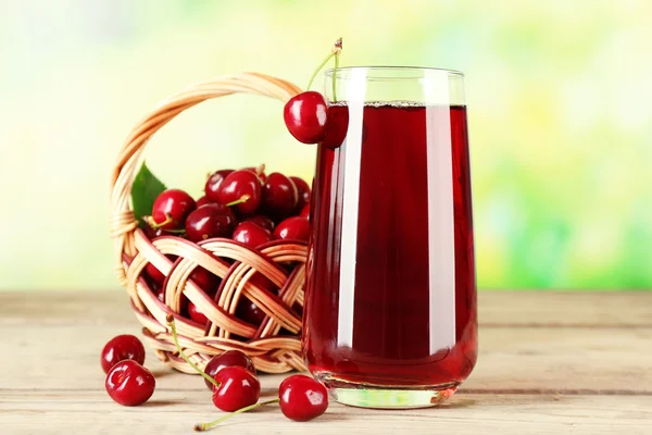 Glass of fresh juice with cherries on bright background — Stock Photo, Image