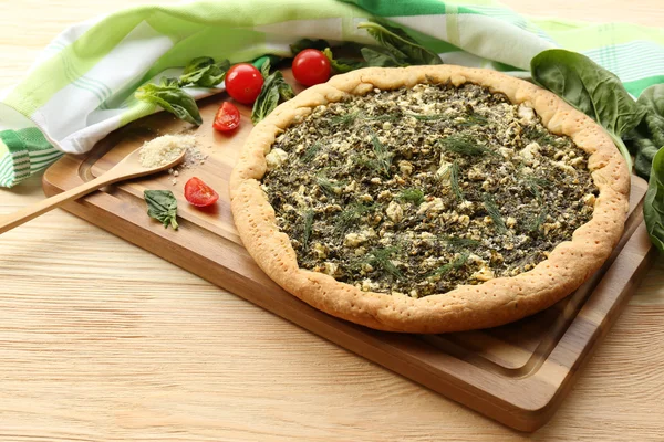 Open pie met spinazie en tomaat kers op tafel close-up — Stockfoto