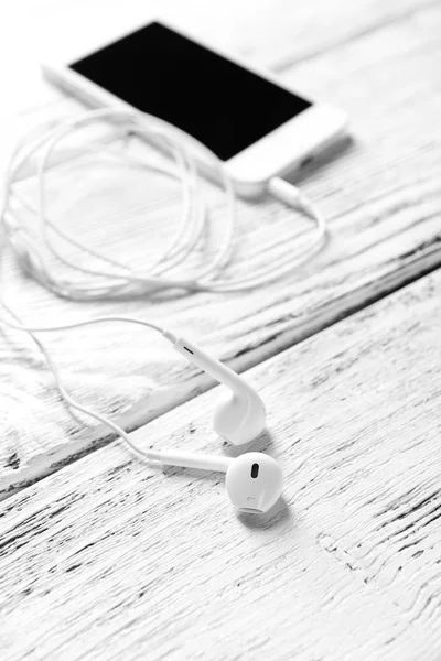 Teléfono móvil y auriculares sobre fondo de madera — Foto de Stock