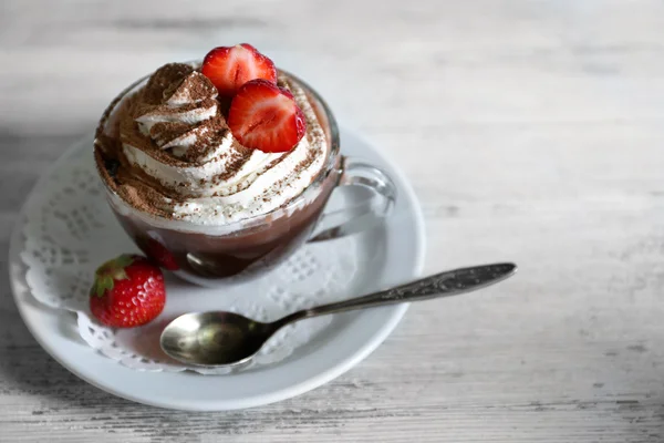 Xícara de café com creme e morango fresco na cor de fundo de madeira — Fotografia de Stock