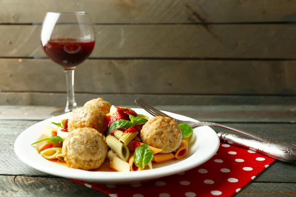 Pasta con albóndigas en plato, copa de vino tinto sobre fondo de mesa de madera —  Fotos de Stock