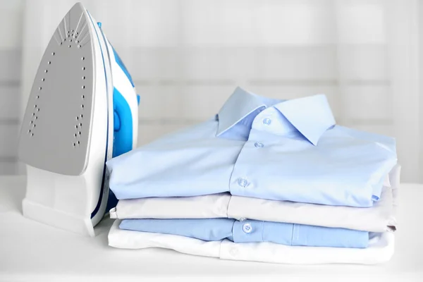 Pile of clothes and electric iron on fabric background — Stock Photo, Image