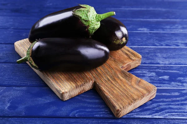 Fresh eggplant on cutting board on wooden background — Stock Photo, Image