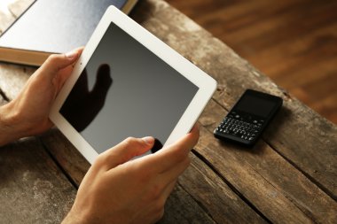 Ahşap masa arka plan üzerinde dijital tablet holding eller