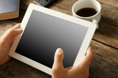 Ahşap masa arka plan üzerinde dijital tablet holding eller