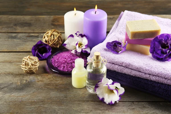 Spa still life with towels, purple flowers and candlelight on wooden background — Stock Photo, Image