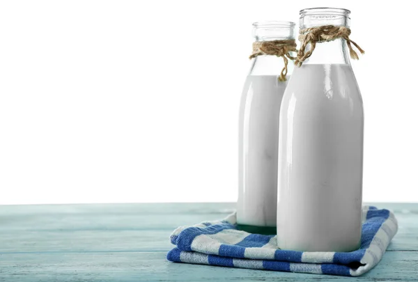 Botellas de vidrio de leche sobre mesa de madera, sobre fondo blanco —  Fotos de Stock