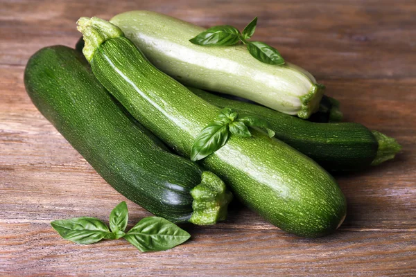 Courgettes fraîches avec courge et basilic sur table en bois close up — Photo