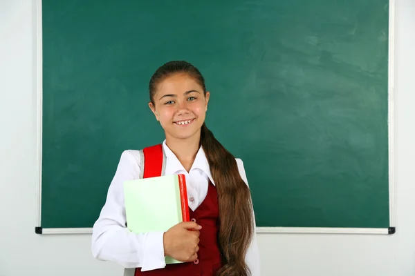 Mooi meisje permanent in de buurt van schoolbord in klas — Stockfoto