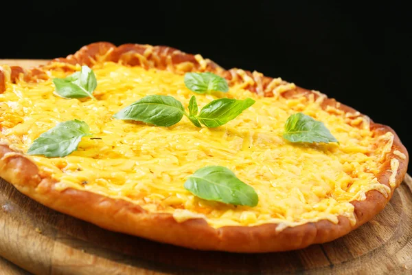 Pizza de queijo saborosa com manjericão sobre fundo preto — Fotografia de Stock