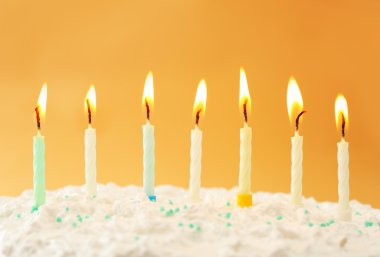 Renkli arkaplanda mumlar olan doğum günü pastası