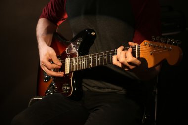 genç adam elektro gitar koyu arka plan üzerinde oynamak