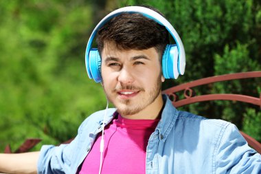 adam parkta bankta oturan kulaklıklar ile