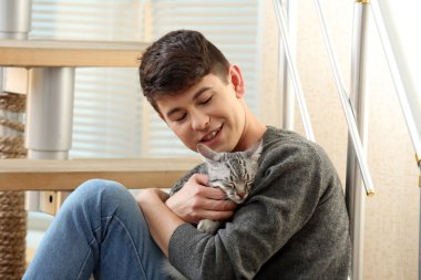 yakışıklı delikanlı ile evde basamaklarında oturan sevimli kedi