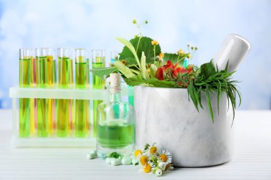 Harç, test tüpleri ve hapları, masada açık renkli otlar