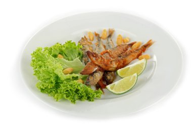 Marul ve üzerinde beyaz izole limon ile plaka üzerinde kızarmış küçük balık