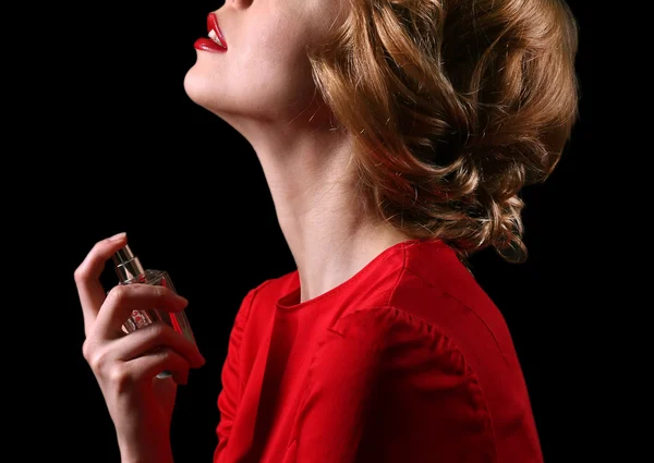 Hermosa joven con botella de perfume sobre fondo negro —  Fotos de Stock