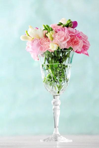 Beautiful spring flowers in glass vase on light blue background