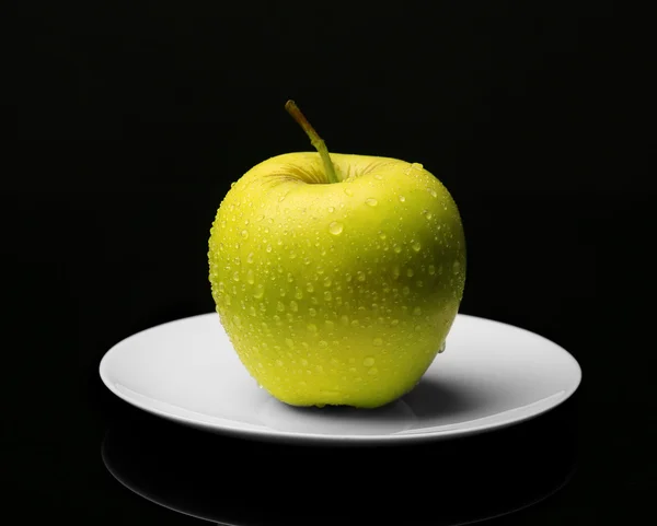 Apple на блюдце на черном фоне — стоковое фото