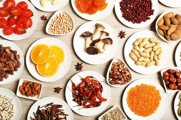 Different products on saucers on wooden table, top view — Stock Photo, Image