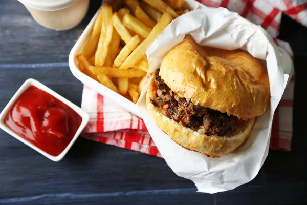 Ízletes burger és hasábburgonyával, fából készült asztal háttér egészségtelen élelmiszer koncepció — Stock Fotó