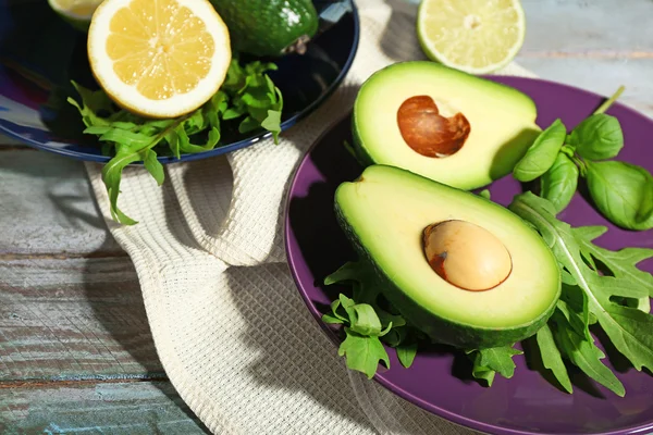 Sliced avocado, arugula and lemon lime on wooden background — Stock Photo, Image