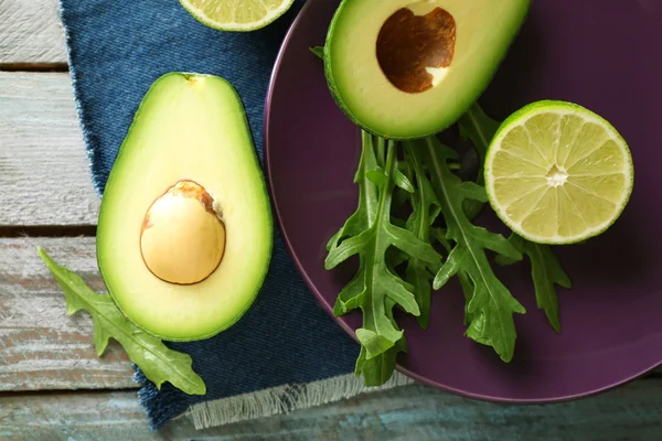 Aguacate en rodajas, rúcula y limón sobre fondo de madera —  Fotos de Stock