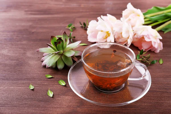 Xícara de chá de ervas com tulipas na mesa de madeira, close-up — Fotografia de Stock