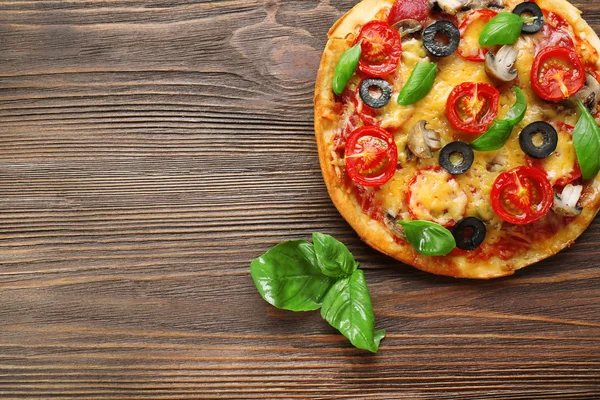 Pizza savoureuse aux légumes et basilic sur fond de bois — Photo